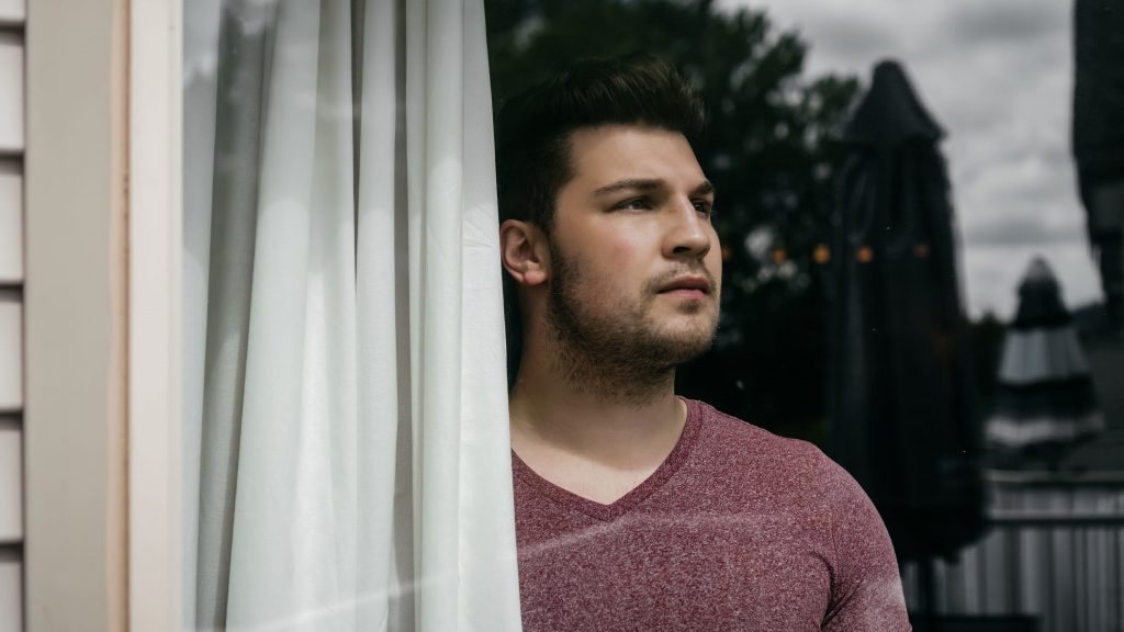 man looking behind a window during lockdown