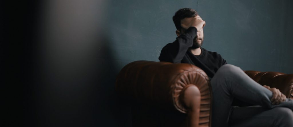 A man is sad and depressed in his sofa on blue Monday